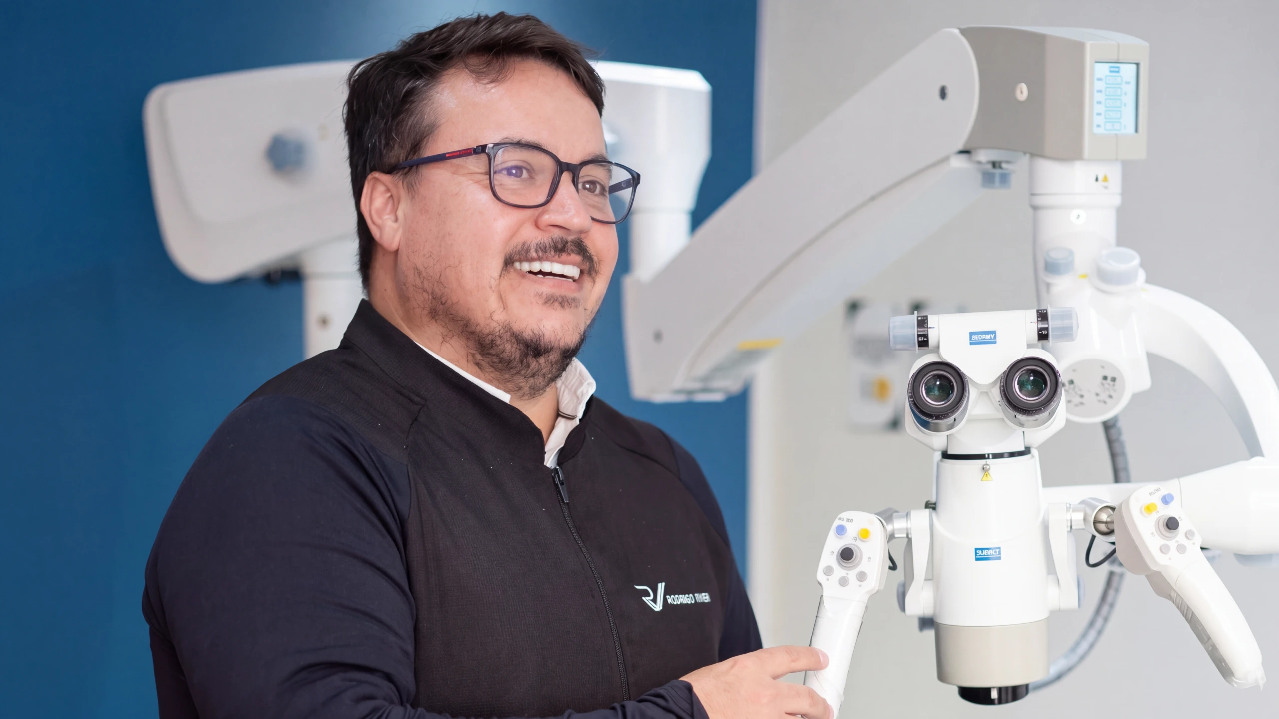 Dr. Rodrigo Vivan ao lado do microscópio odontológico